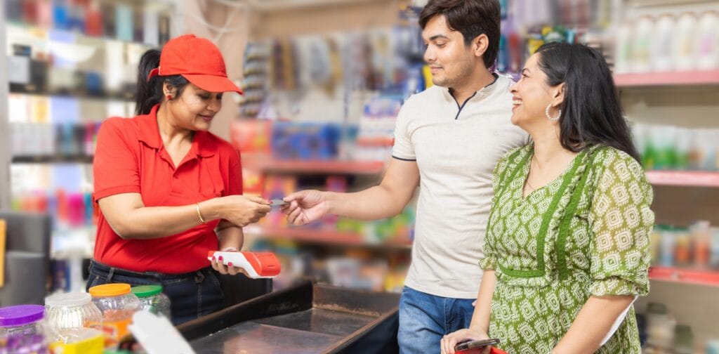 Indian couple at grocery store or supermarket using credit or debit card for digital payment. indian female cashier taking card for payment digital india concept.