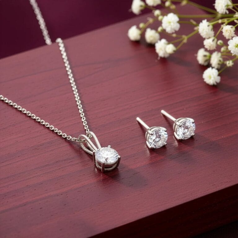 Silver necklace with a round solitaire pendant and matching stud earrings placed on a wooden surface.